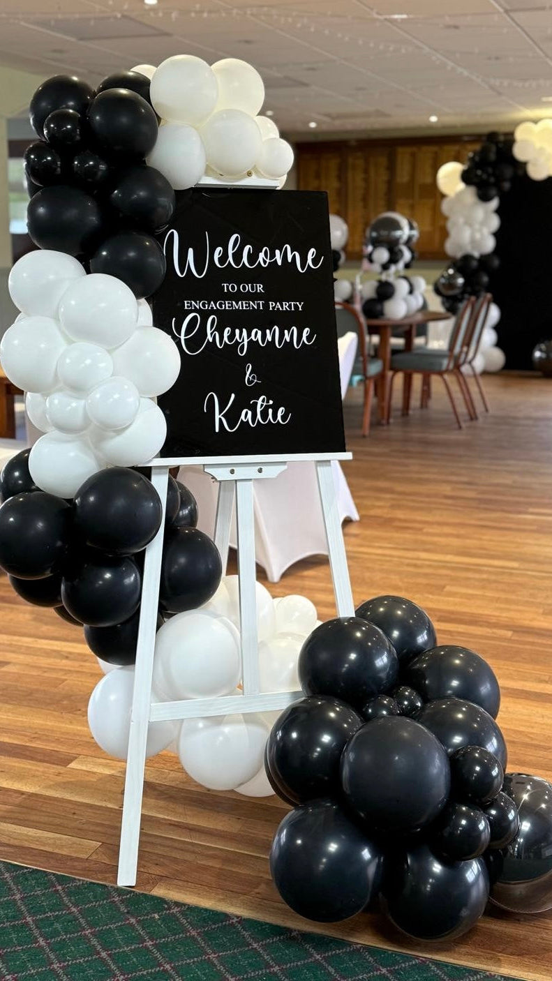 Engagement party setup with black and white balloons and a welcome sign.